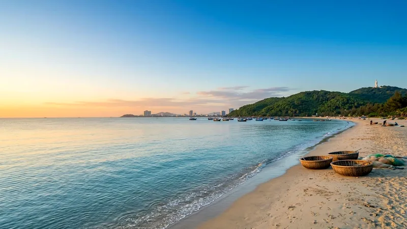 Sunrise over My Khe Beach with basket boats and Son Tra Peninsula in distance