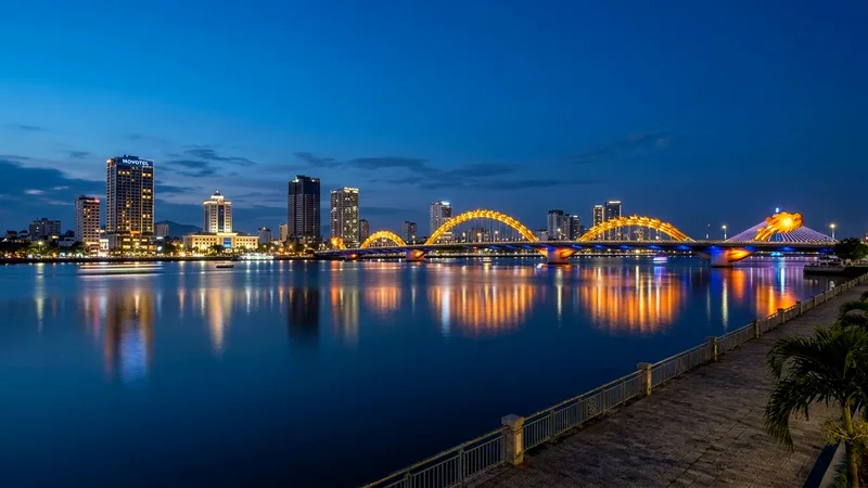 Dragon Bridge lit gold over the Han River with Da Nang skyline at dusk